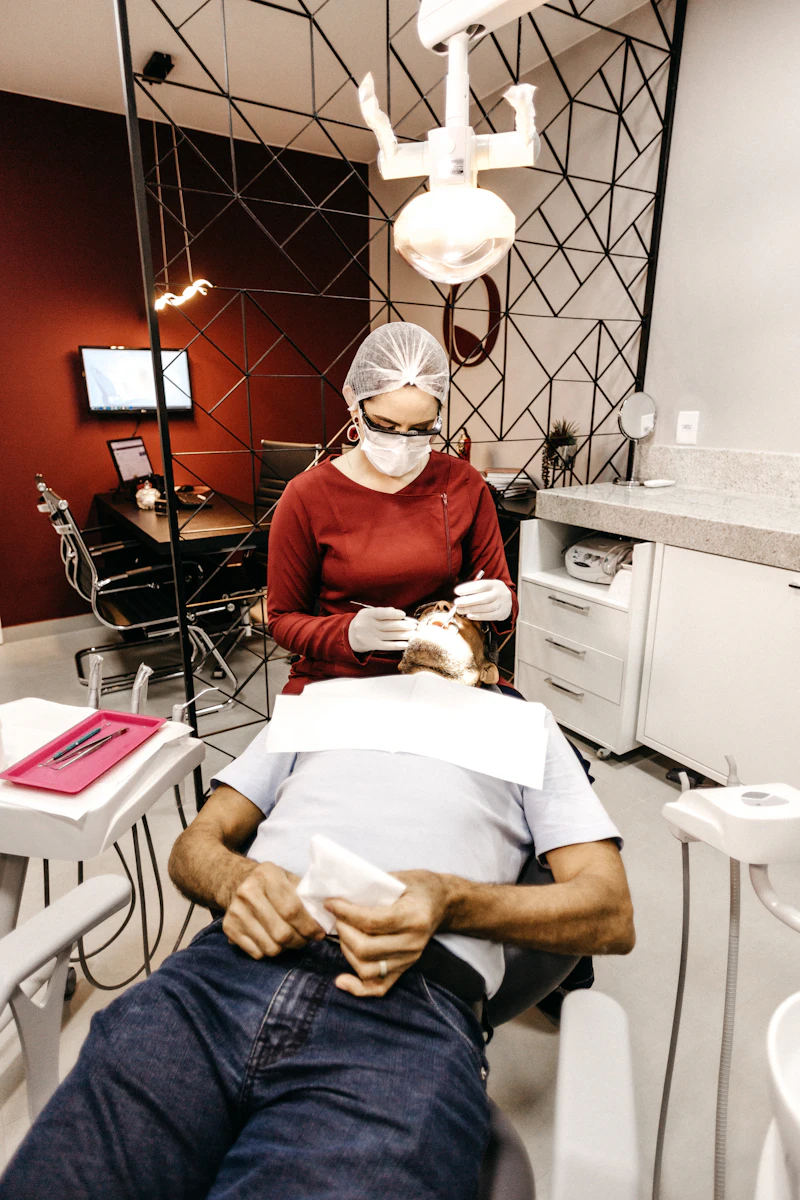 A dentist in a mask checking a patient's teeth in a bright dental room