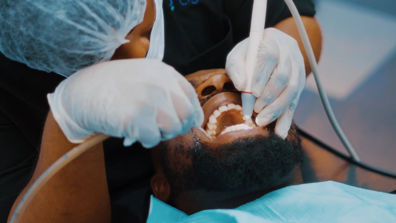 A dentist working on a man's teeth with a small instrument