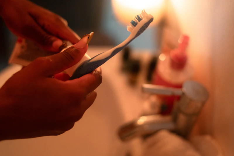 Toothpaste being squeezed onto a toothbrush under warm evening light